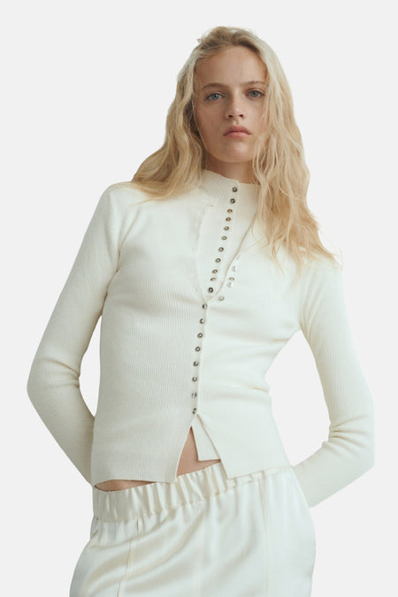 Beige geribd gilet van MANGO met zilveren drukknoppen en witte satijnen broek.