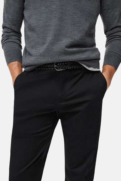 Pantalon de saison bleu foncé de MANGO, porté avec un pull gris et une ceinture tressée noire.