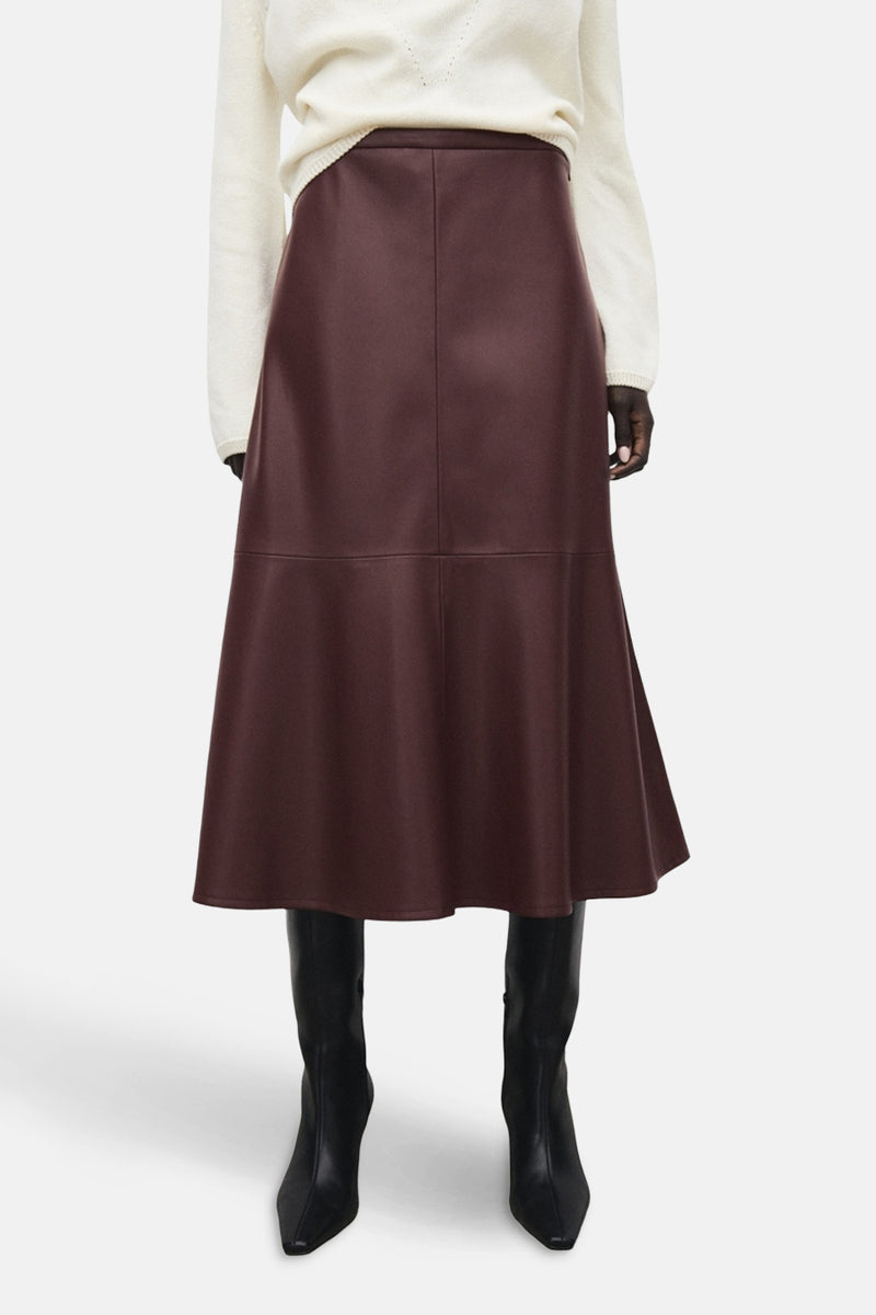 Jupe longue bordeaux de MANGO, avec une coupe évasée et portée avec un pull blanc et des bottes noires.
