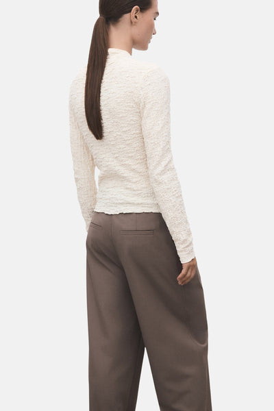T-shirt beige à manches longues de MANGO, texturé, porté avec un pantalon marron ample, vue arrière.
