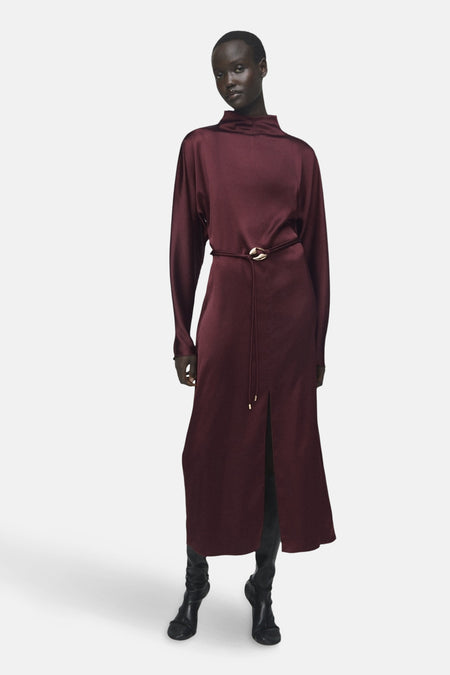 Bordeaux lange mouwen jurk van MANGO, met een bijpassende ceintuur en gedragen met zwarte enkellaarsjes.
