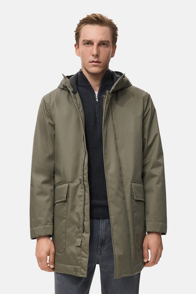 Veste courte kaki de MANGO, avec capuche et fermeture à zip, portée sur un pull gris et un jean.
