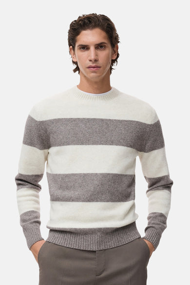Pull à col rond multicolore de MANGO, à rayures horizontales larges, porté avec un pantalon marron.
