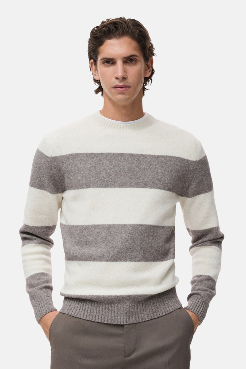 Pull à col rond multicolore de MANGO, à rayures horizontales larges, porté avec un pantalon marron.
