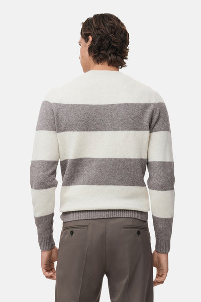 Pull à col rond multicolore de MANGO, à rayures horizontales blanches et grises, porté avec un pantalon marron.