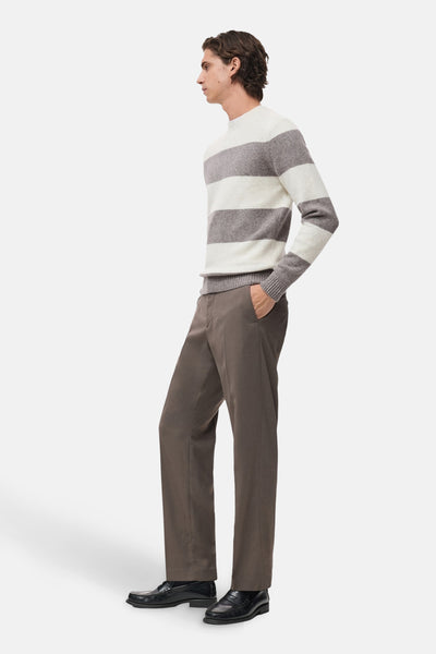 Pull à col rond multicolore de MANGO, rayures horizontales grises et blanches, porté avec un pantalon marron.