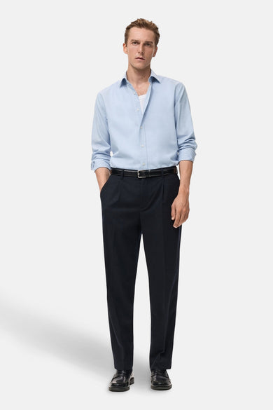 Chemise à manches longues bleue de MANGO, portée avec un pantalon foncé et une ceinture noire.