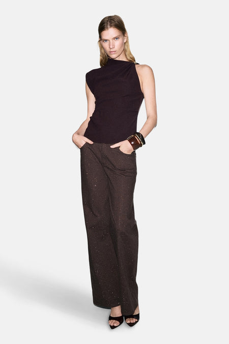 Chemisier sans manches brun de MANGO, porté avec un pantalon scintillant et un bracelet en cuir.