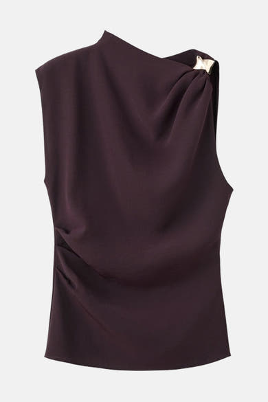 Bruine mouwloze bruine blouse van MANGO, met een draperie over de schouder vastgehouden door een gouden versiering.