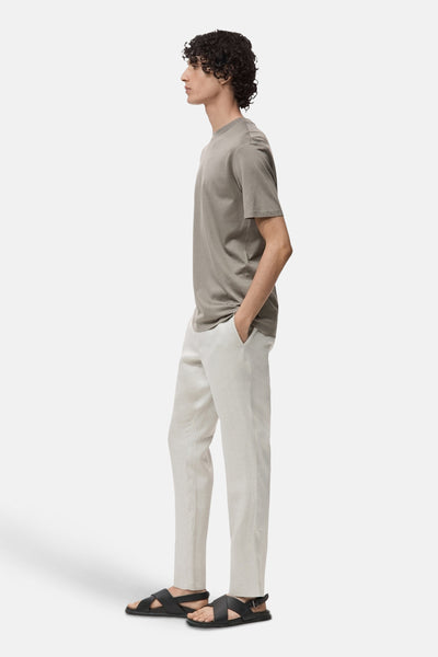 Grijze T-shirt met korte mouwen van MANGO, gedragen met een beige broek en zwarte sandalen, zijwaarts bekeken.