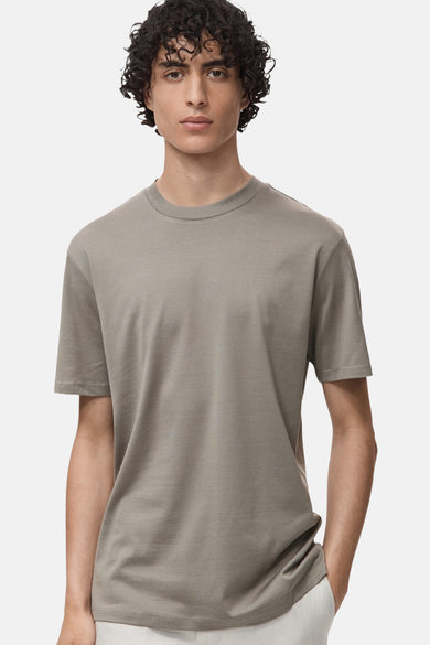 Grijze T-shirt met korte mouwen van MANGO, gedragen door een man met krullend haar.