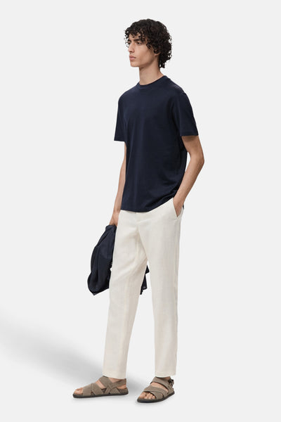 Blauw T-shirt met korte mouwen van MANGO, gedragen met een beige linnen broek en gekruiste sandalen.