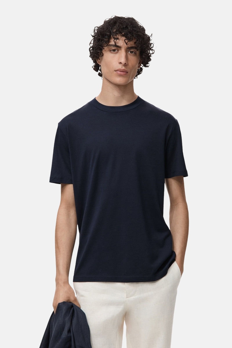 Blauw T-shirt met korte mouwen van MANGO, gedragen met een beige broek en een bijpassend jasje in de hand.