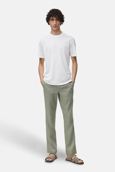 T-shirt à manches courtes blanc de MANGO, porté avec un pantalon vert et des sandales.