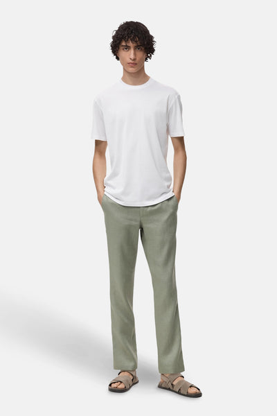 T-shirt à manches courtes blanc de MANGO, porté avec un pantalon vert et des sandales.