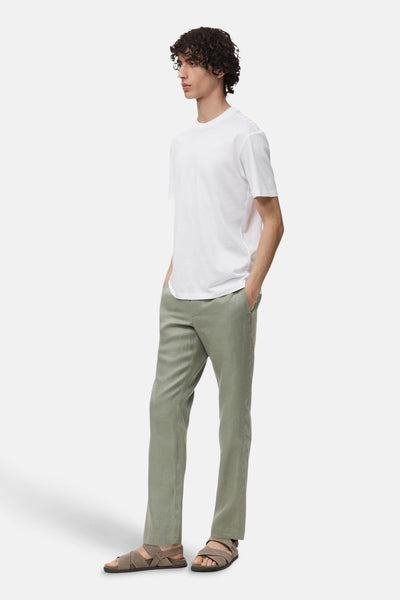 Wit T-shirt met korte mouwen van MANGO, gedragen met een groene broek en sandalen met gekruiste bandjes.