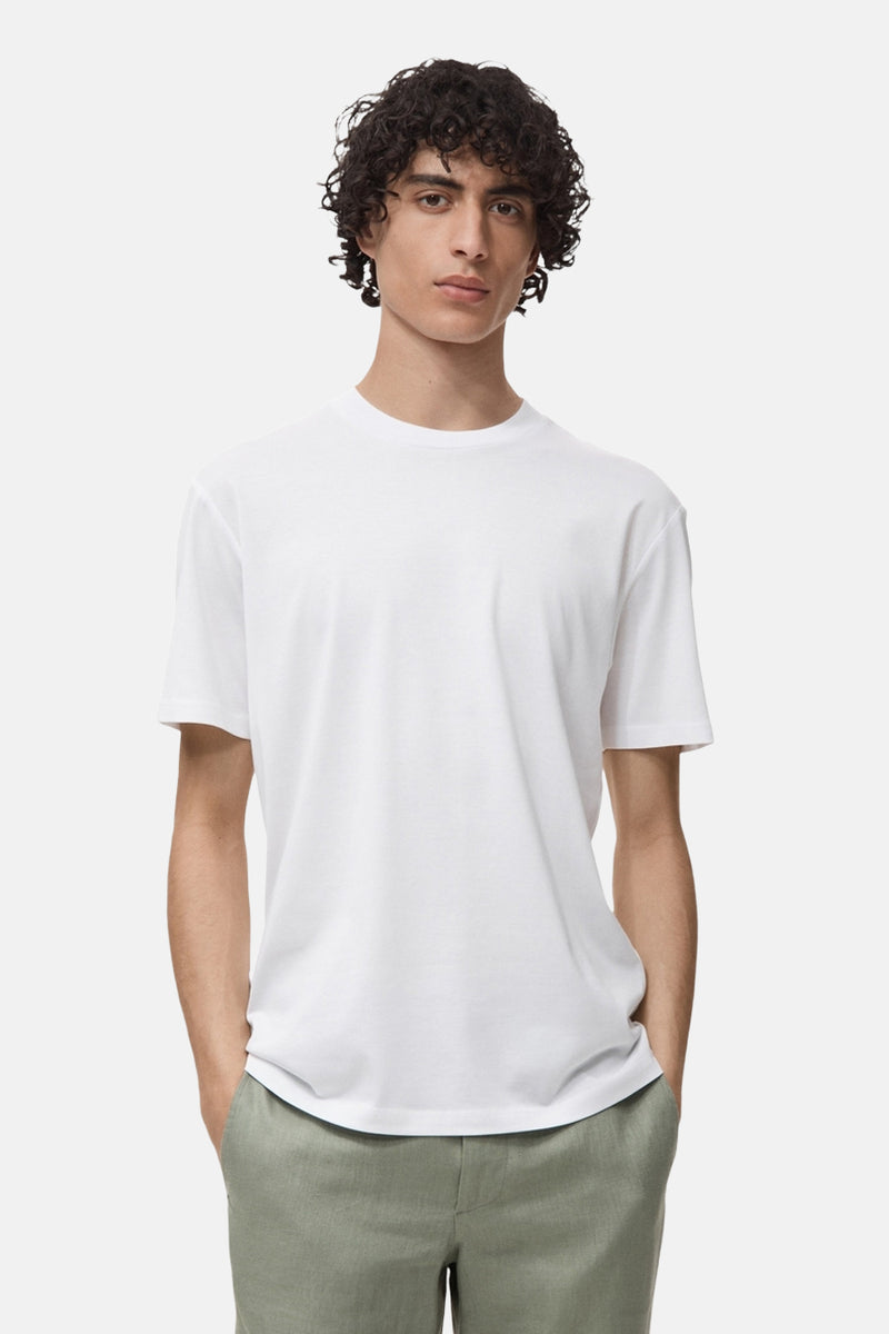 T-shirt blanc à manches courtes de MANGO, porté avec un pantalon décontracté vert olive.