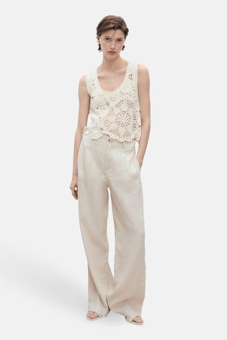 Ecru mouwloos topje van MANGO, versierd met ingewikkelde gehaakte patronen en gedragen met een beige wijde broek.