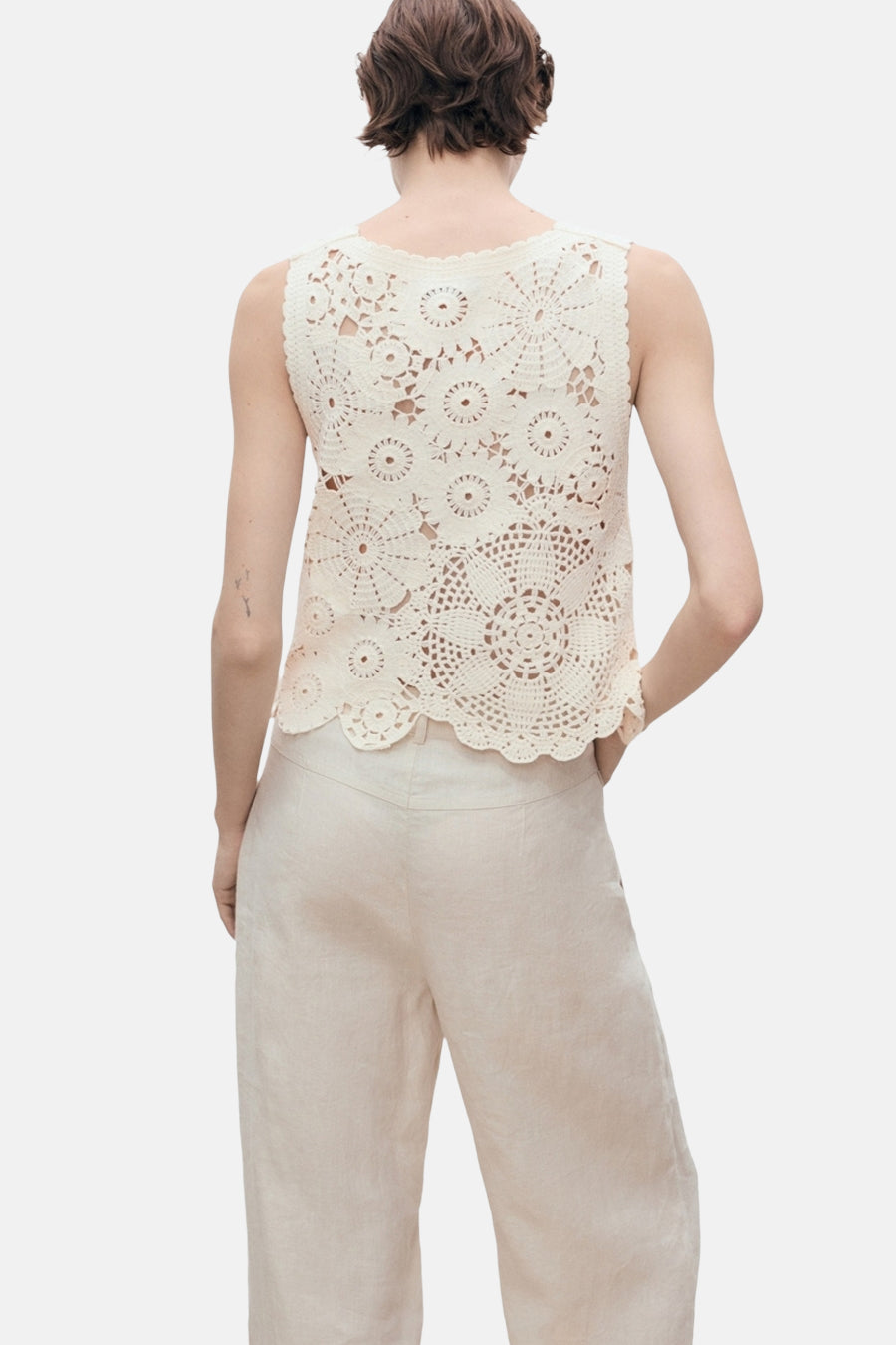 Ecru mouwloos topje van MANGO, bloemenhaakpatroon, gedragen met een beige linnen broek.