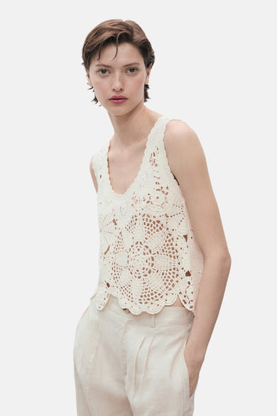 Top écru in crochet van MANGO, gedragen met een linnen broek met hoge taille.