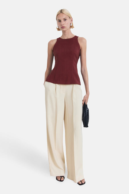 Bordeaux mouwloos blouse van MANGO, gedragen met een crèmekleurige broek en sandalen.