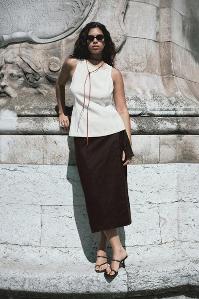Ecru blouse van MANGO met rode strikjes, gedragen met een bruine rok en zwarte hakken.