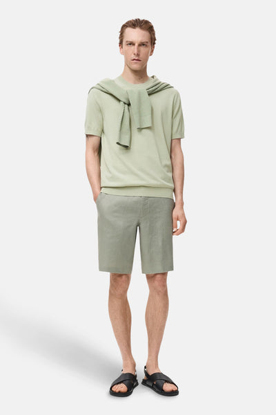 Groen T-shirt met korte mouwen van MANGO, gedragen met een trui die over de schouders is geknoopt en een bijpassende short.