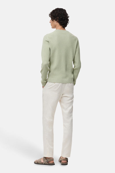Groene trui met ronde hals van MANGO, geribbelde textuur, gedragen met een lichte broek en leren sandalen, achterzicht.