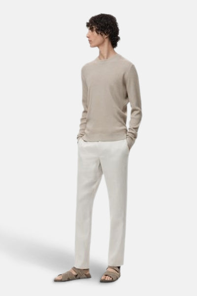 Beige ronde hals trui van MANGO, gedragen met een witte linnen broek en bruine sandalen, in zijaanzicht.