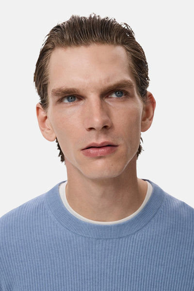 Blauwe trui met ronde hals van MANGO, in ribgebreide stof, gedragen over een wit T-shirt.