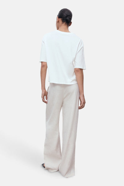 T-shirt blanc à manches courtes de MANGO, porté avec un pantalon fluide beige en lin.
