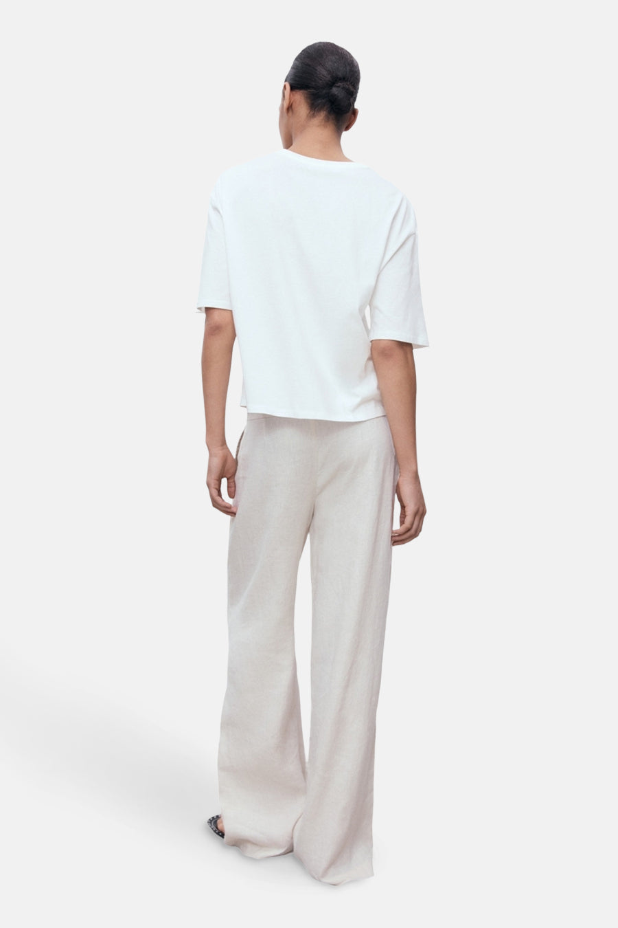 Wit T-shirt met korte mouwen van MANGO, gedragen met een beige linnen broek met wijde pijpen.