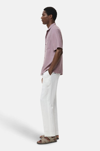 Chemise violette à manches courtes de MANGO, portée avec un pantalon blanc et des sandales croisées, vue de côté.