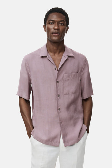 Paarse blouse met korte mouwen van MANGO, met borstzak en een relaxte pasvorm, gedragen met een witte broek.