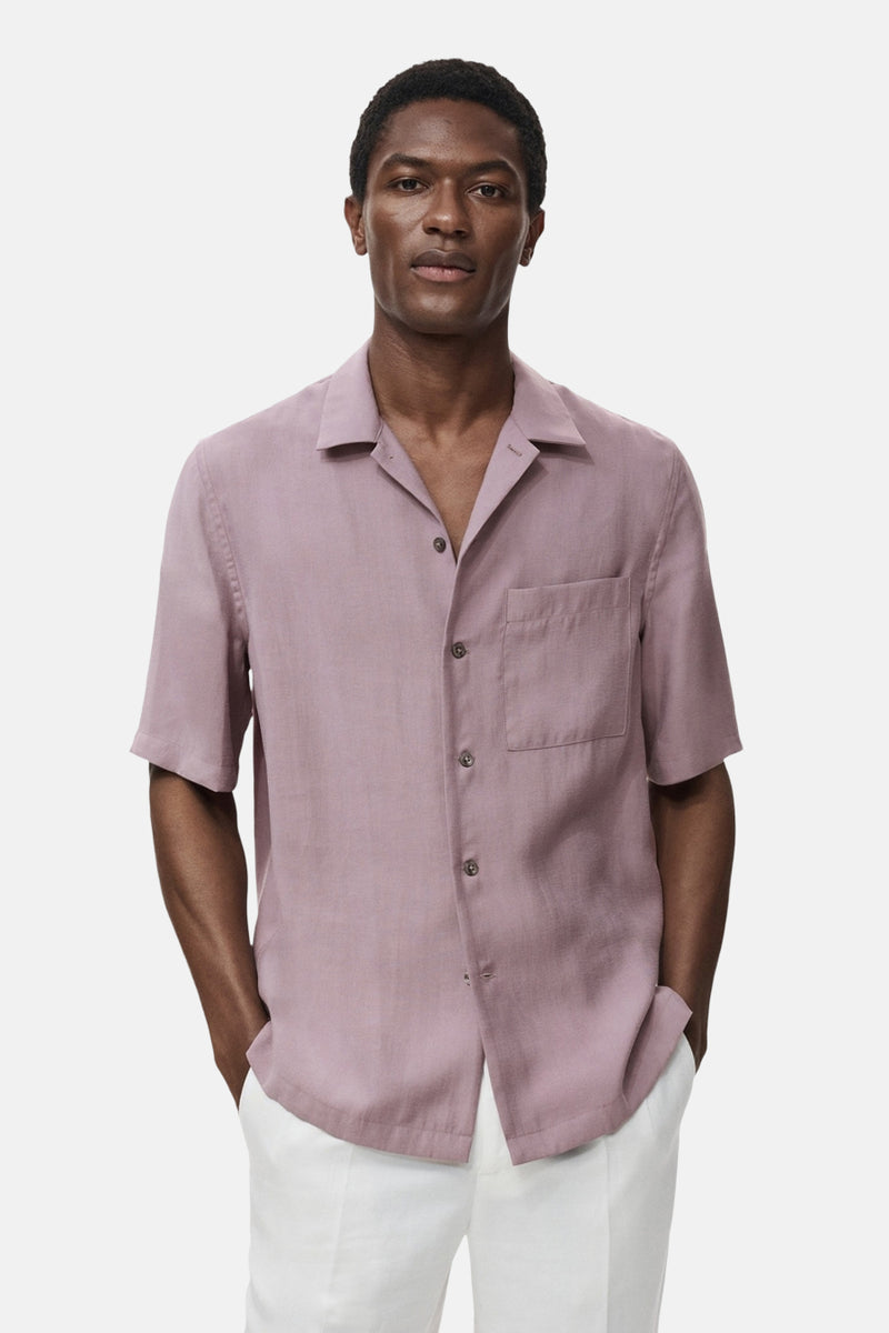 Paarse blouse met korte mouwen van MANGO, met borstzak en een relaxte pasvorm, gedragen met een witte broek.
