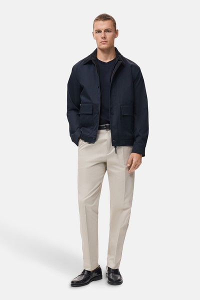 Blauw T-shirt met korte mouwen van MANGO, gedragen onder een marineblauwe jas met een beige broek en zwarte schoenen.