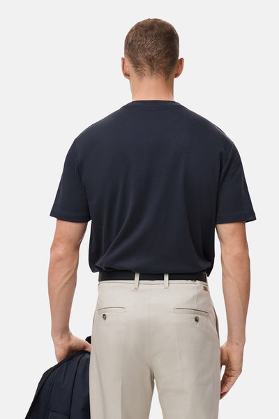 T-shirt à manches courtes bleu marine de MANGO, vu de dos, porté avec un pantalon beige.