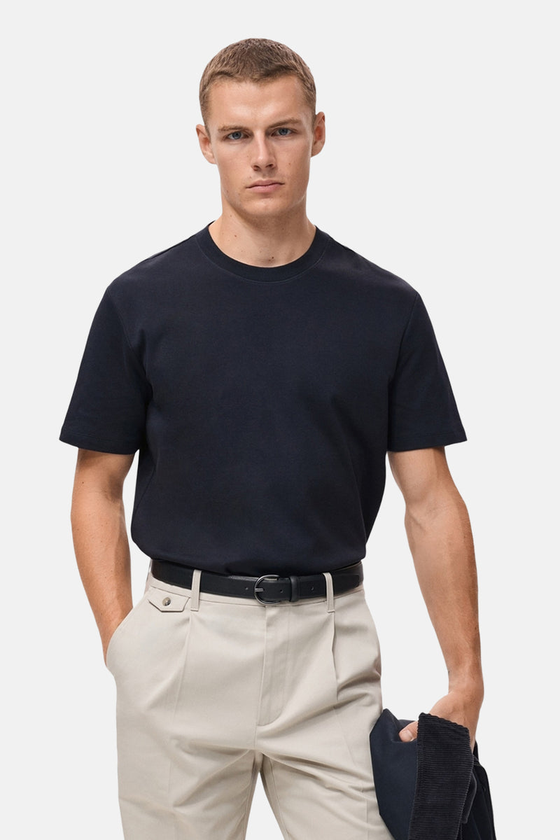 Marineblauwe T-shirt met korte mouwen van MANGO, van achteren gezien, gedragen met een beige broek.