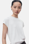 Top blanc en tricot de MANGO, porté avec des boucles d'oreilles rondes contrastées.