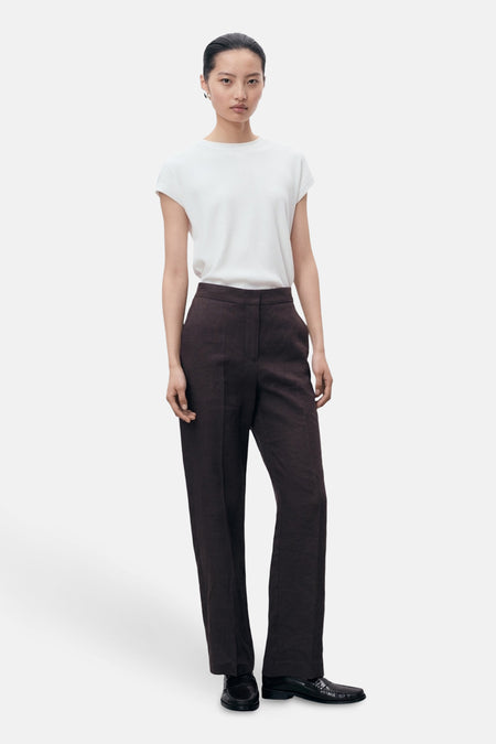 Wit topje van MANGO, gedragen met een bruine broek met hoge taille en zwarte schoenen.