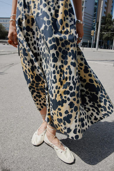 Lange veelkleurige rok van MANGO, met luipaardprint op een beige achtergrond, gedragen met veterschoenen.