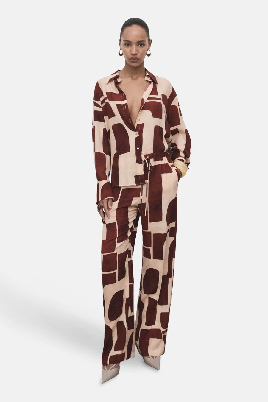 Pantalon multicolore de MANGO avec imprimé géométrique marron et beige, porté avec une chemise assortie.