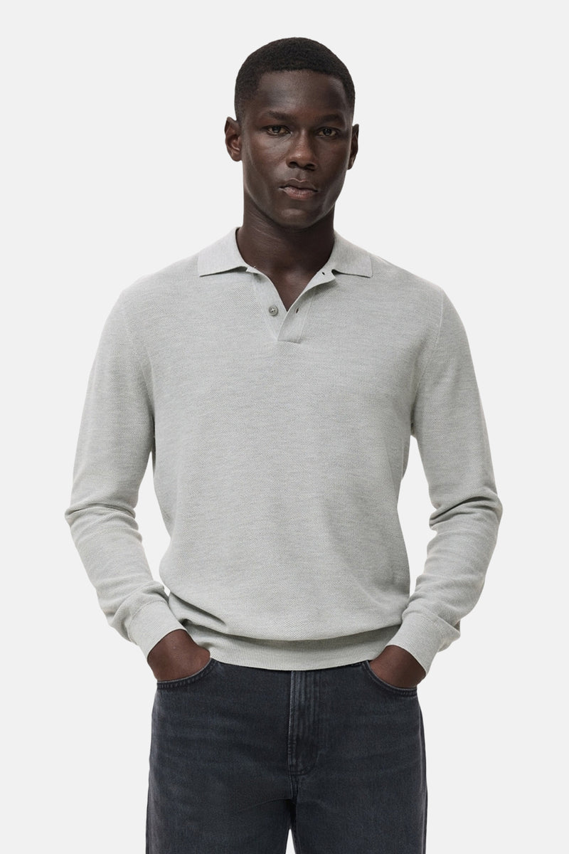Grijze trui met ronde hals van MANGO, gedragen met een donkere jeans en handen in de zakken.