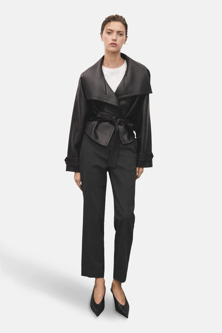 Grijze gestreepte broek van MANGO, gedragen met een witte top en een geknoopte zwarte jas.