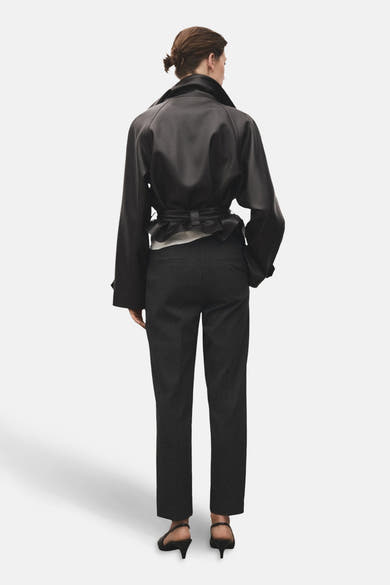 Pantalon gris van MANGO, porté avec une veste noire et des escarpins noirs, vue de dos.
