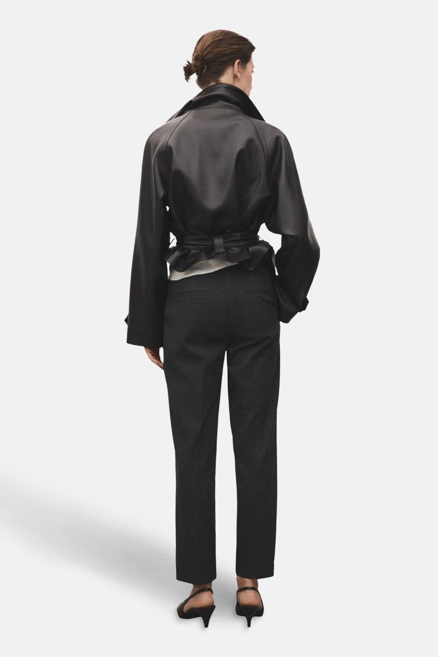 Pantalon gris van MANGO, porté avec une veste noire et des escarpins noirs, vue de dos.
