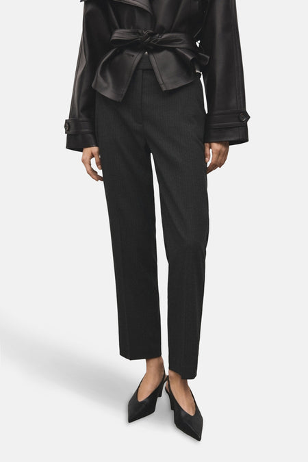 Grijze gestreepte broek van MANGO, gedragen met een geknoopte zwarte leren jas en zwarte puntige pumps.