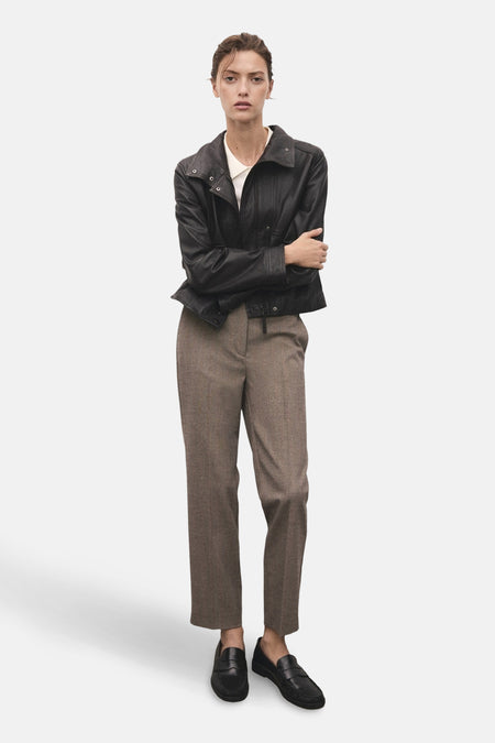 Pantalon brun chiné de MANGO, porté avec une veste en cuir noire et des chaussures mocassins noires.