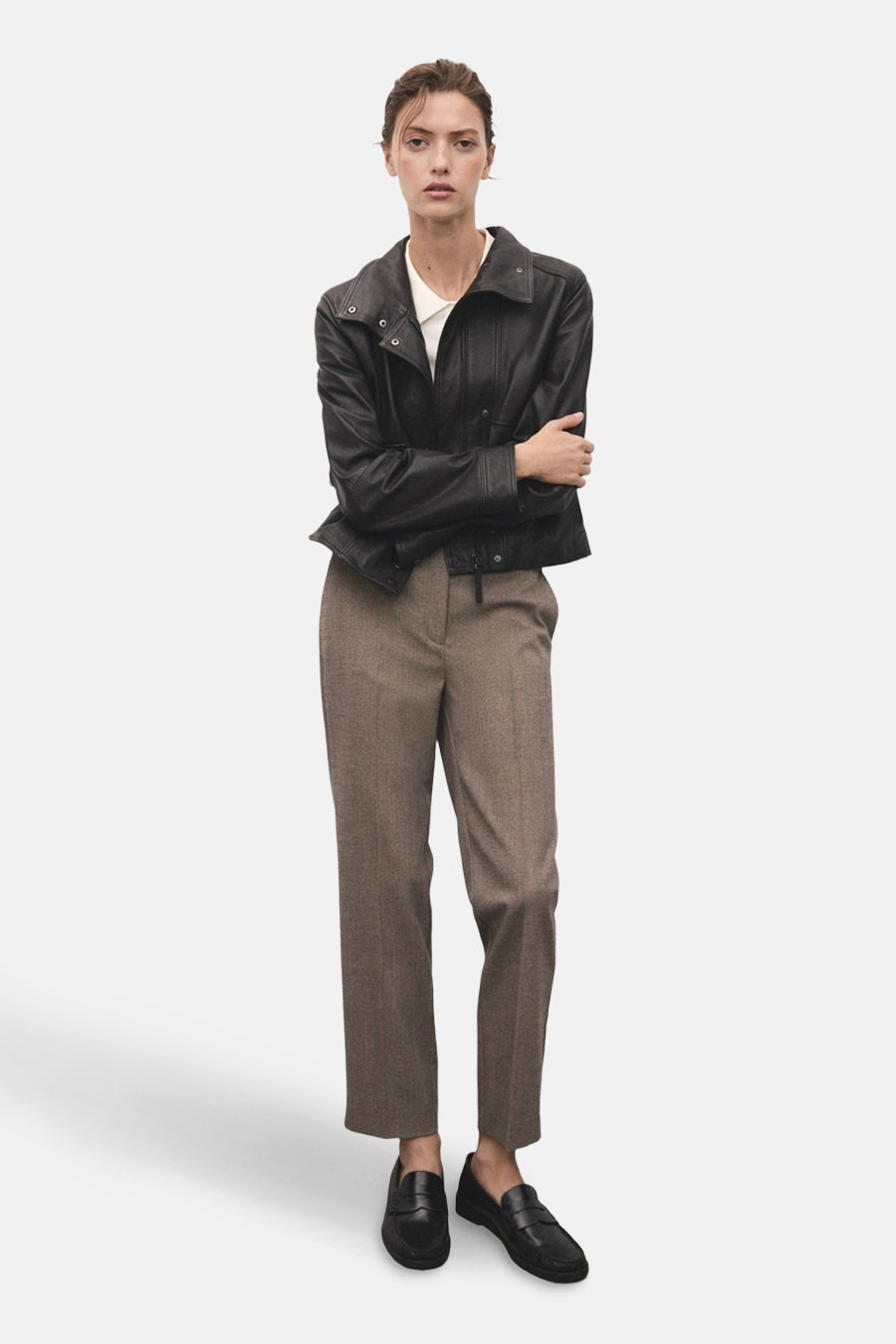 Pantalon brun chiné de MANGO, porté avec une veste en cuir noire et des chaussures mocassins noires.