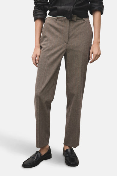Pantalon marron à carreaux de MANGO, avec des plis nets et des mocassins noirs en cuir.
